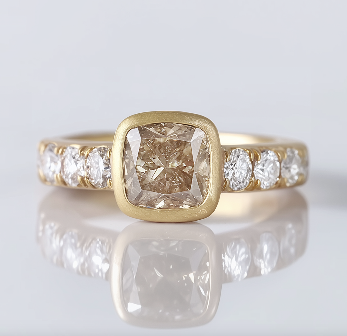 Gold ring with a large square diamond and smaller diamonds on a reflective surface