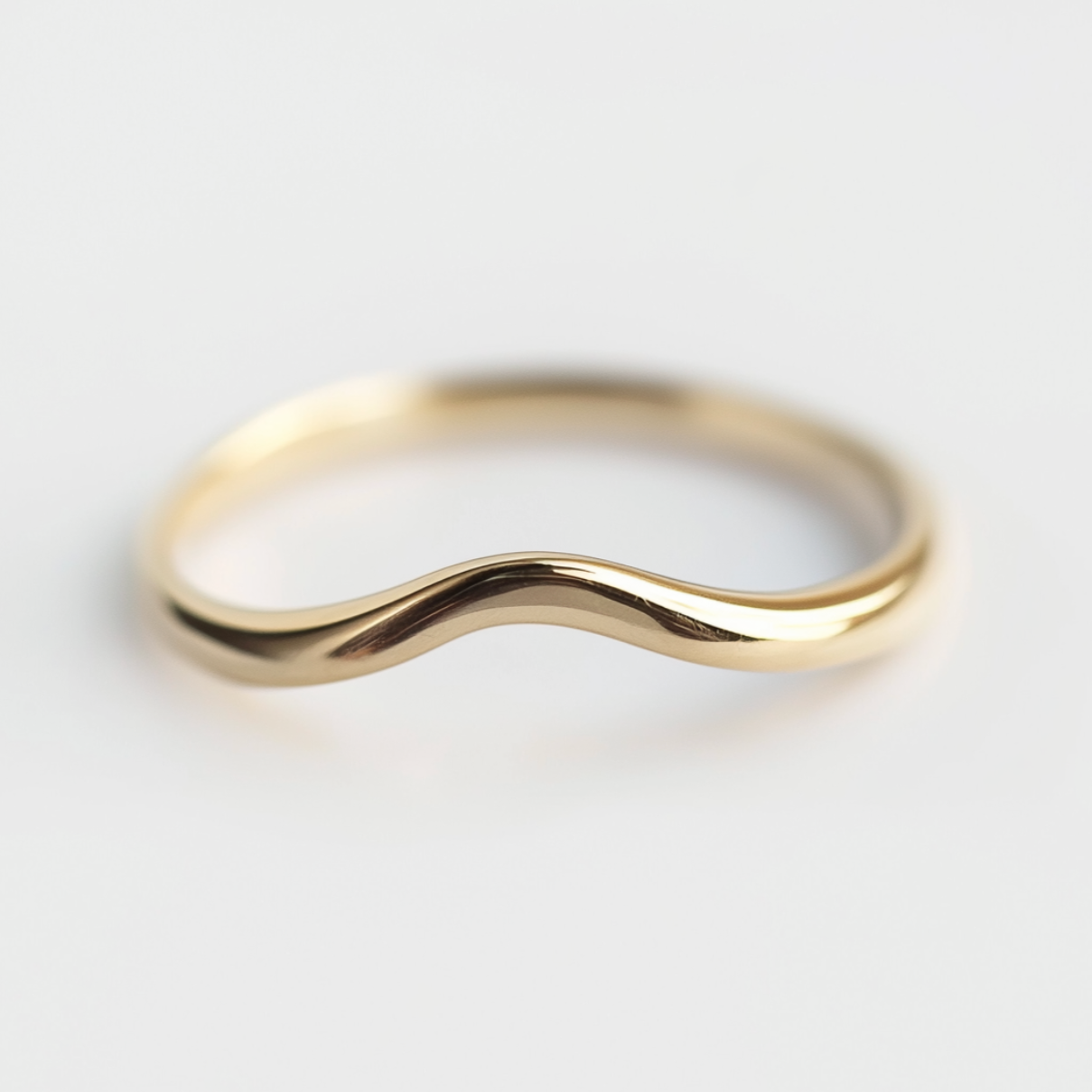 A curved gold wedding band with a smooth, shiny finish.