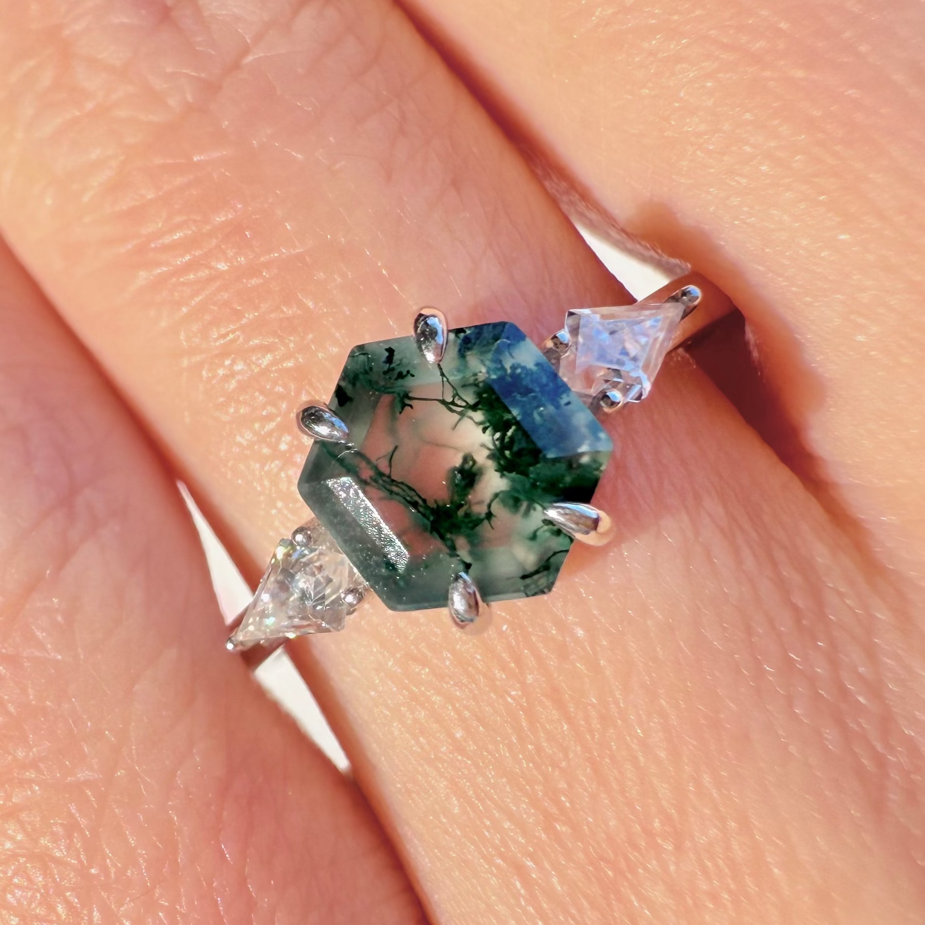 Close-up of a hand wearing a ring with a green gemstone.