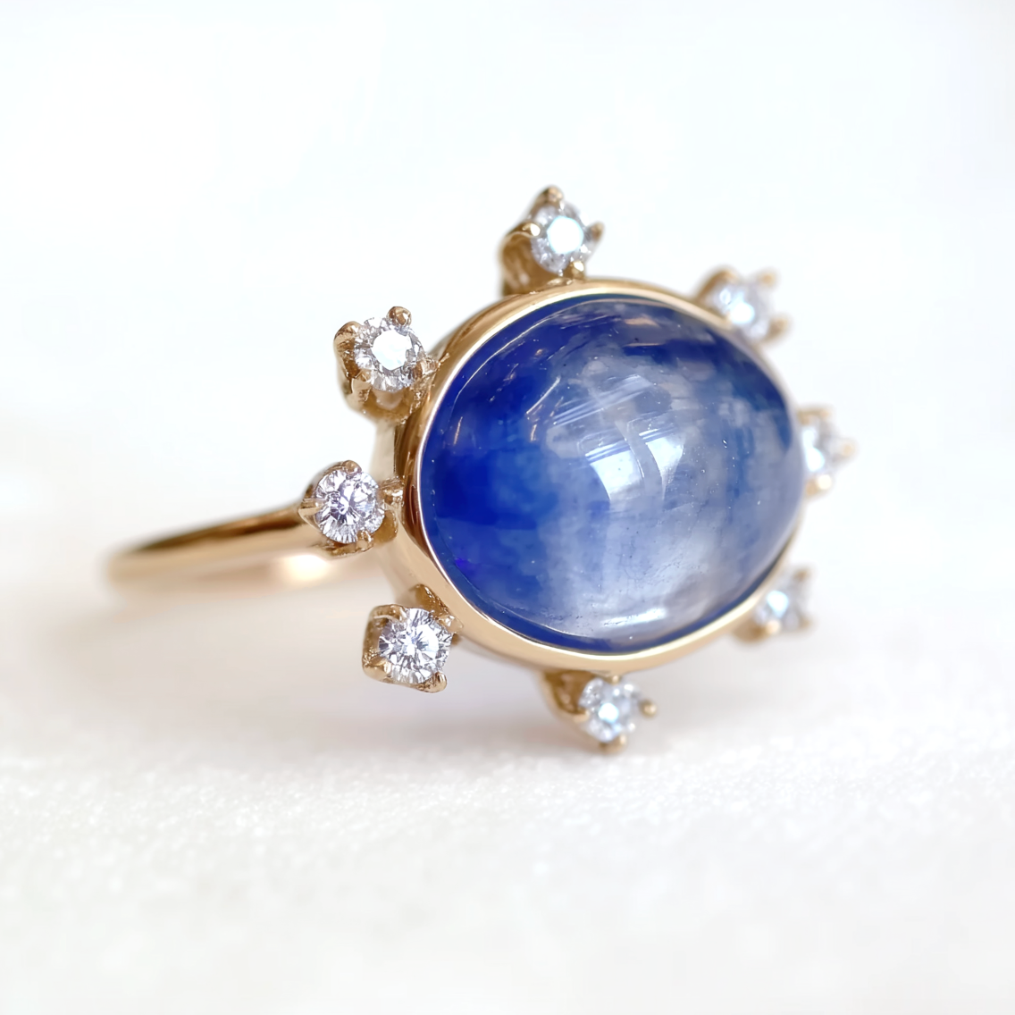 Gold ring with a large cabochon blue sapphire and smaller diamonds on a white background