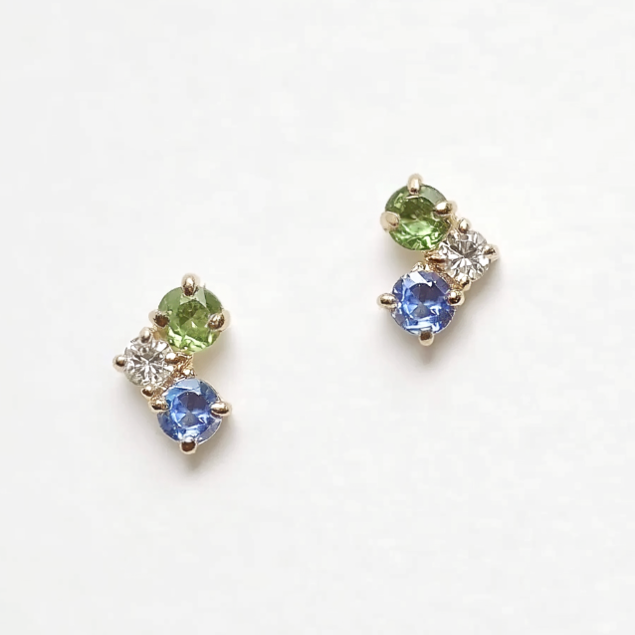 Pair of earrings with green and blue gemstones on a white background