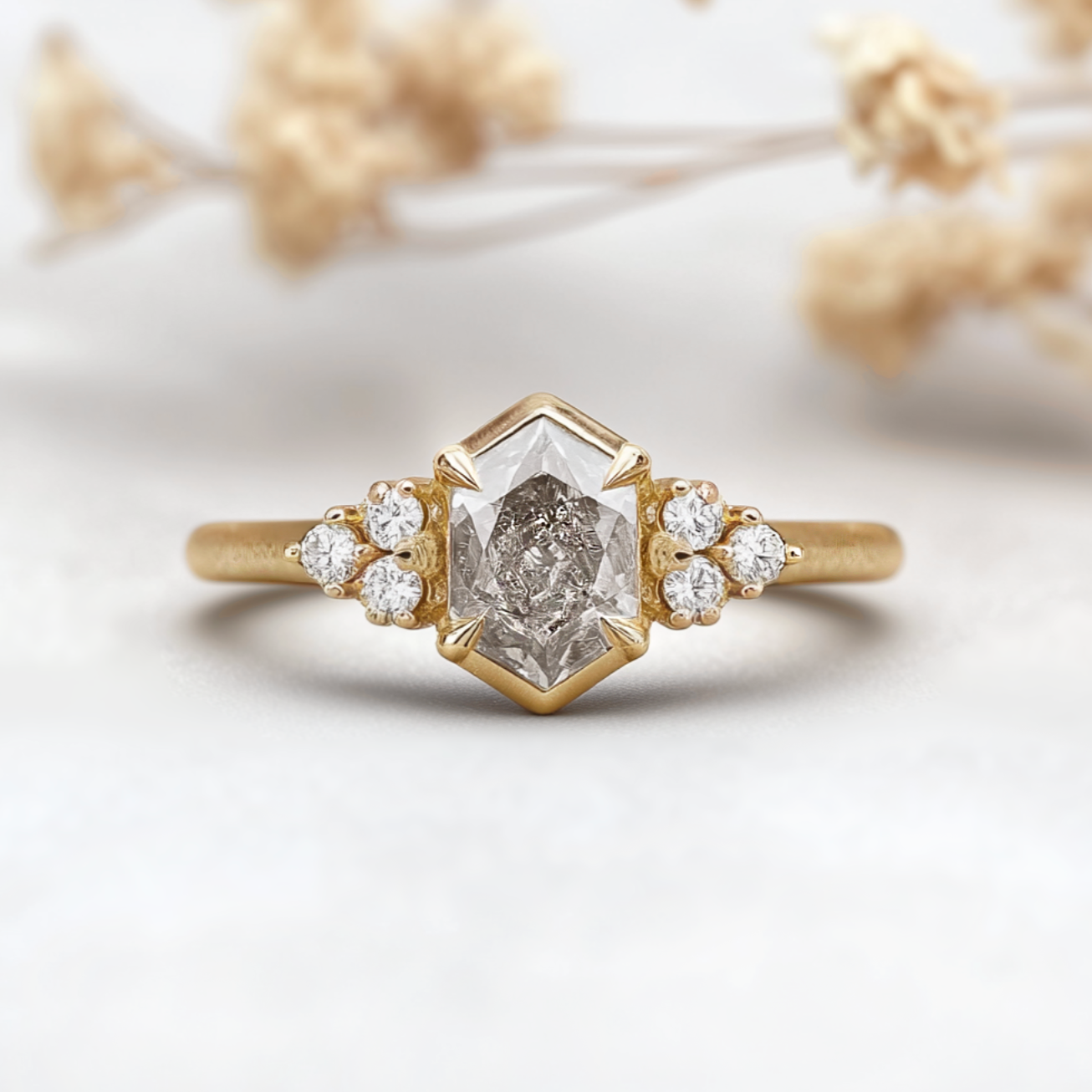 Gold ring with a central diamond and smaller diamonds on a light background