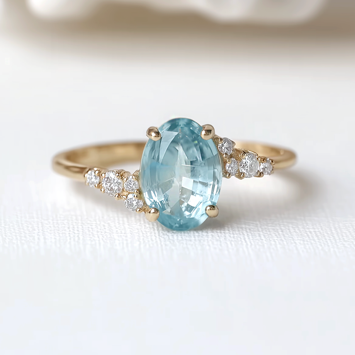 Gold ring with a large blue gemstone and smaller diamonds on a white background