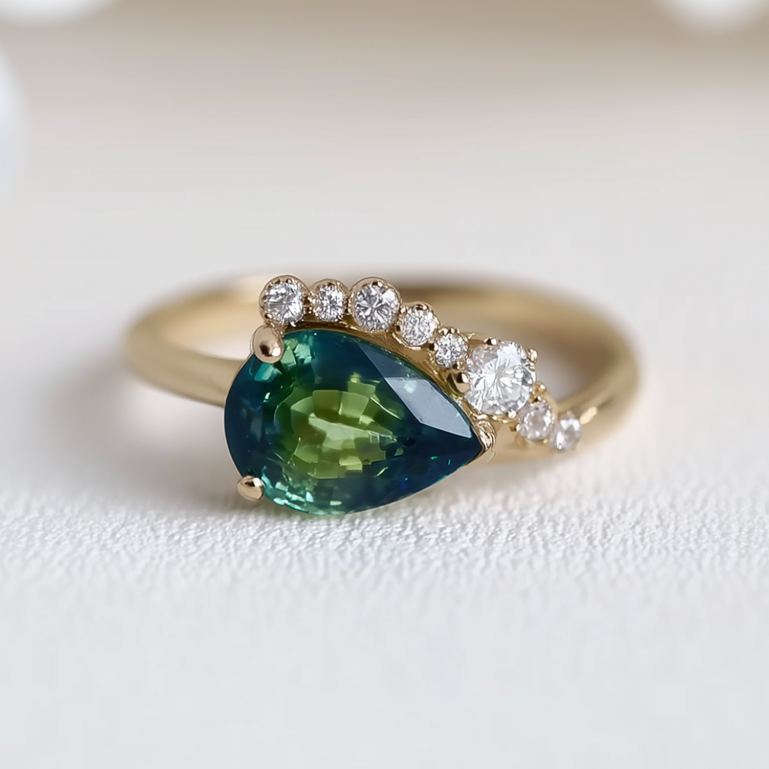 Gold ring with a green gemstone and diamond accents on a light background