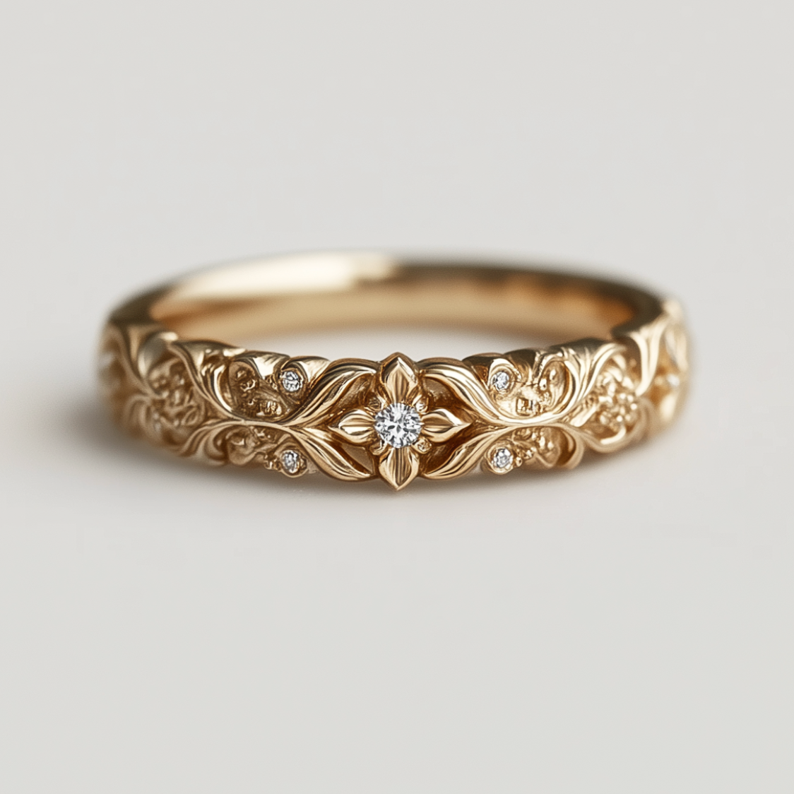 Gold ring with intricate floral design and diamond center on a light gray background