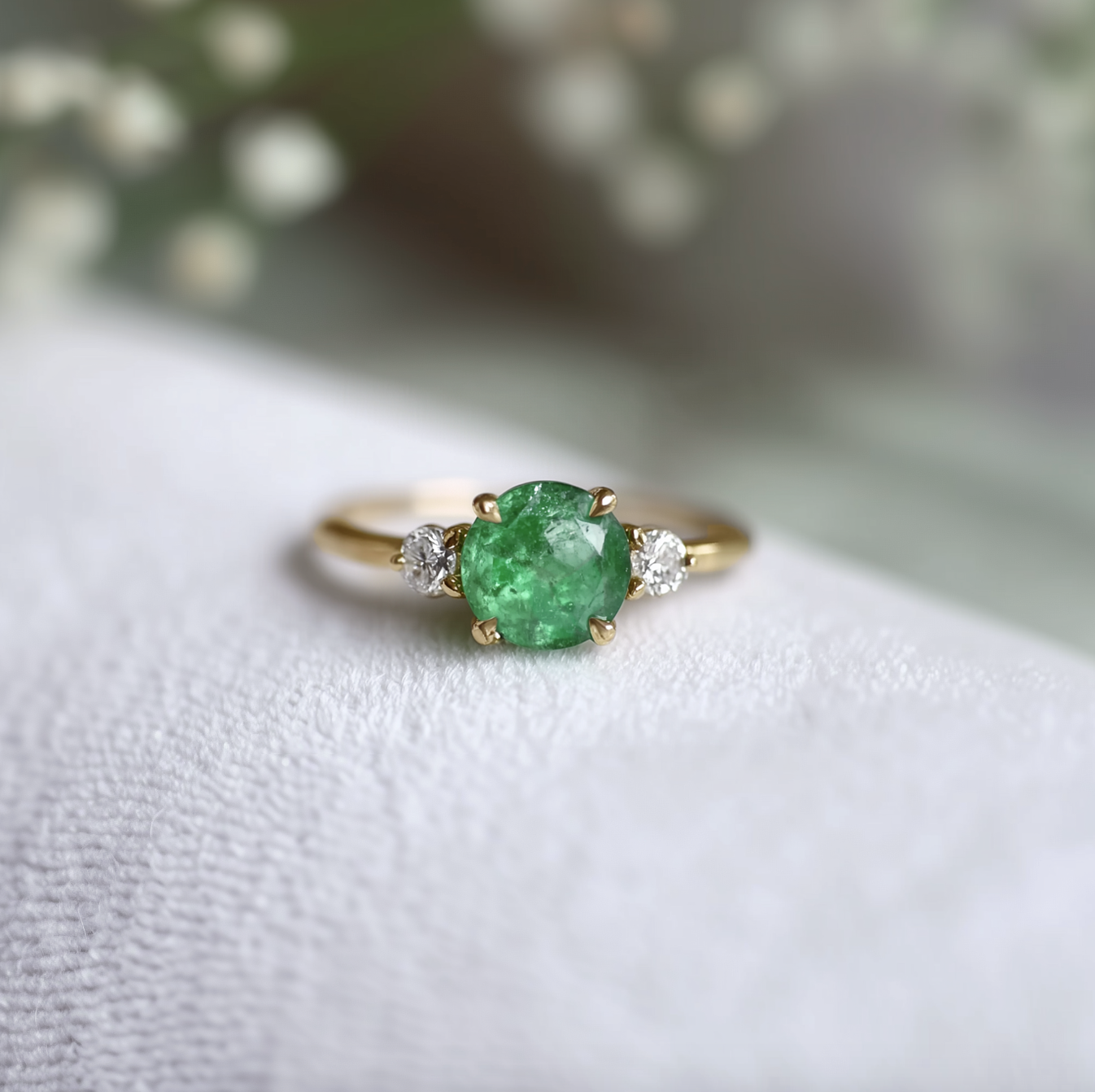 Gold ring with a green gemstone on a white surface