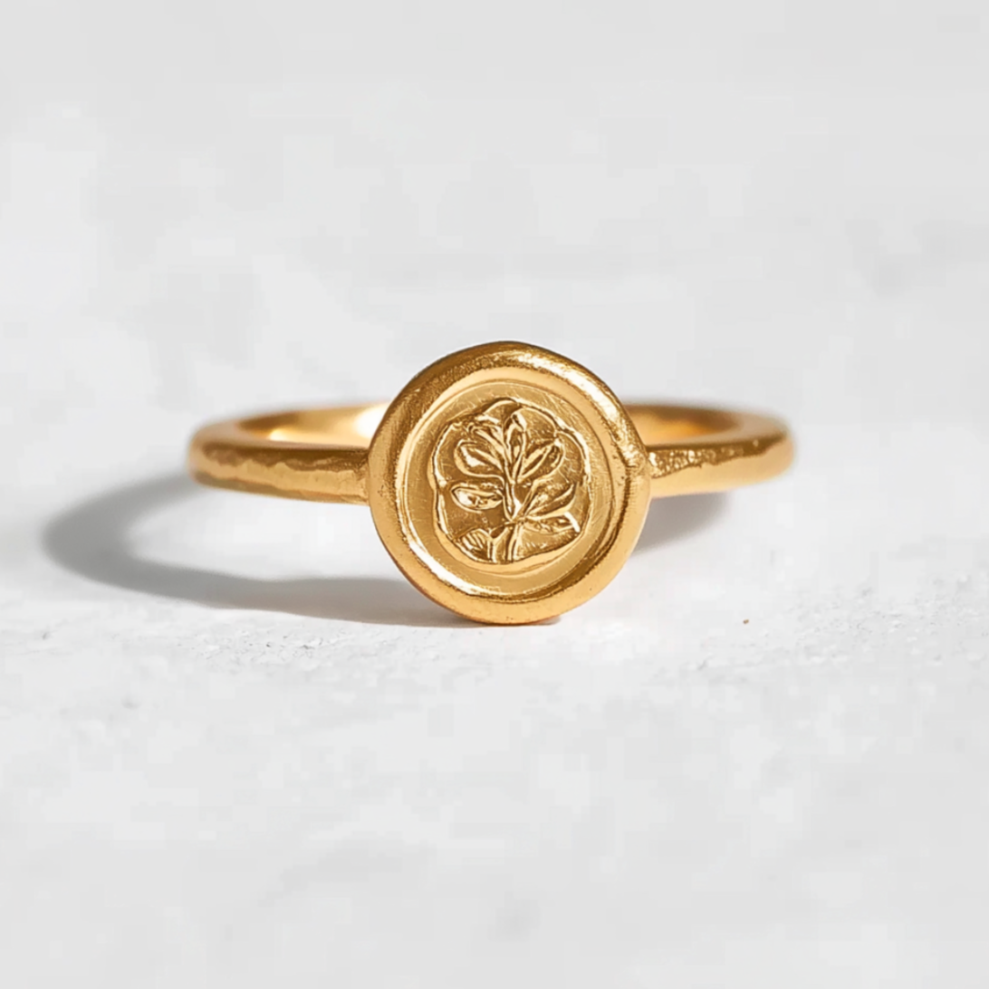 A 24k gold ring with an embossed laurel leaf design on a white background.