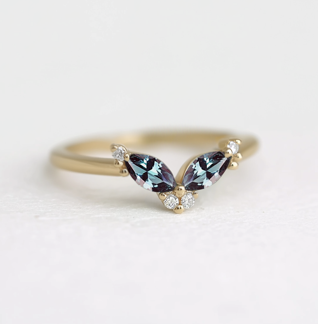 Gold ring with two marquise-shaped gemstones on a white background