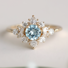 Load image into Gallery viewer, Gold ring with a blue gemstone and smaller diamonds on a light background
