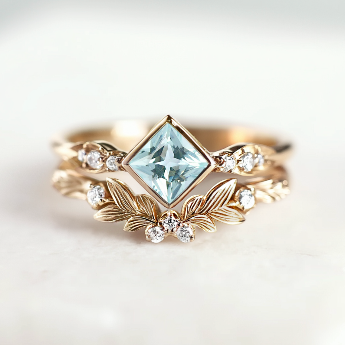 Gold ring with a central blue gemstone and leaf-like design on a light background