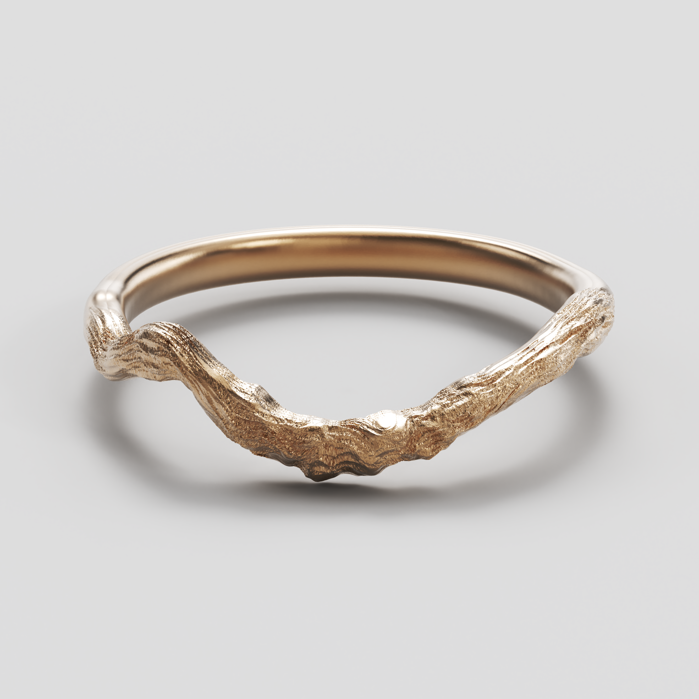Gold ring with a natural, branch-like design on a gray background