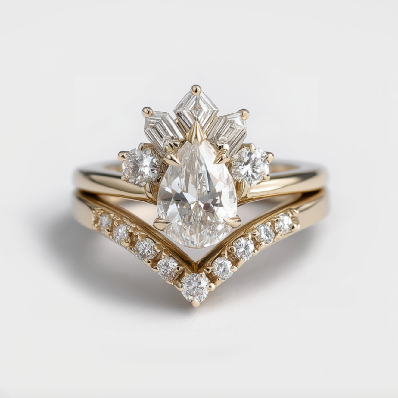 Gold ring with pear-shaped diamond and smaller diamonds on a light gray background