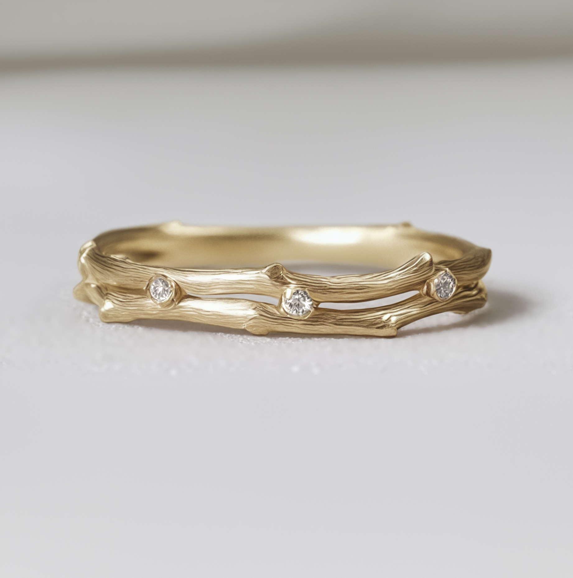 Gold ring with diamond accents on a light gray background