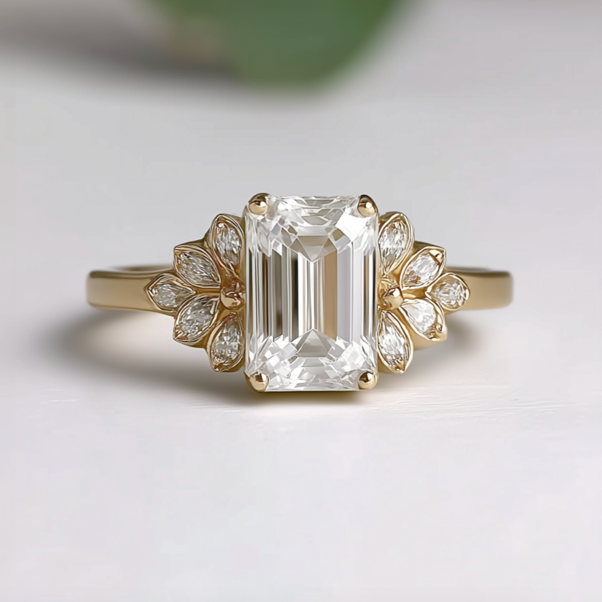 Gold ring with emerald-cut diamond and floral design on a light background