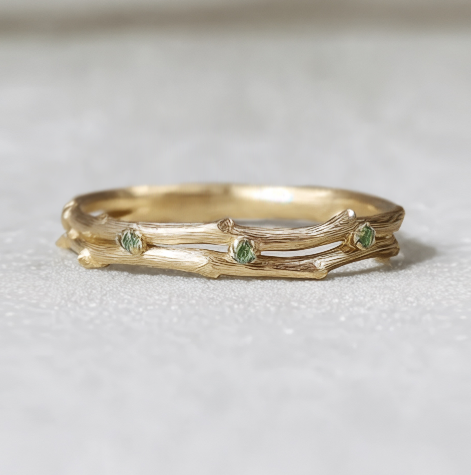Gold ring with green gemstones on a white background