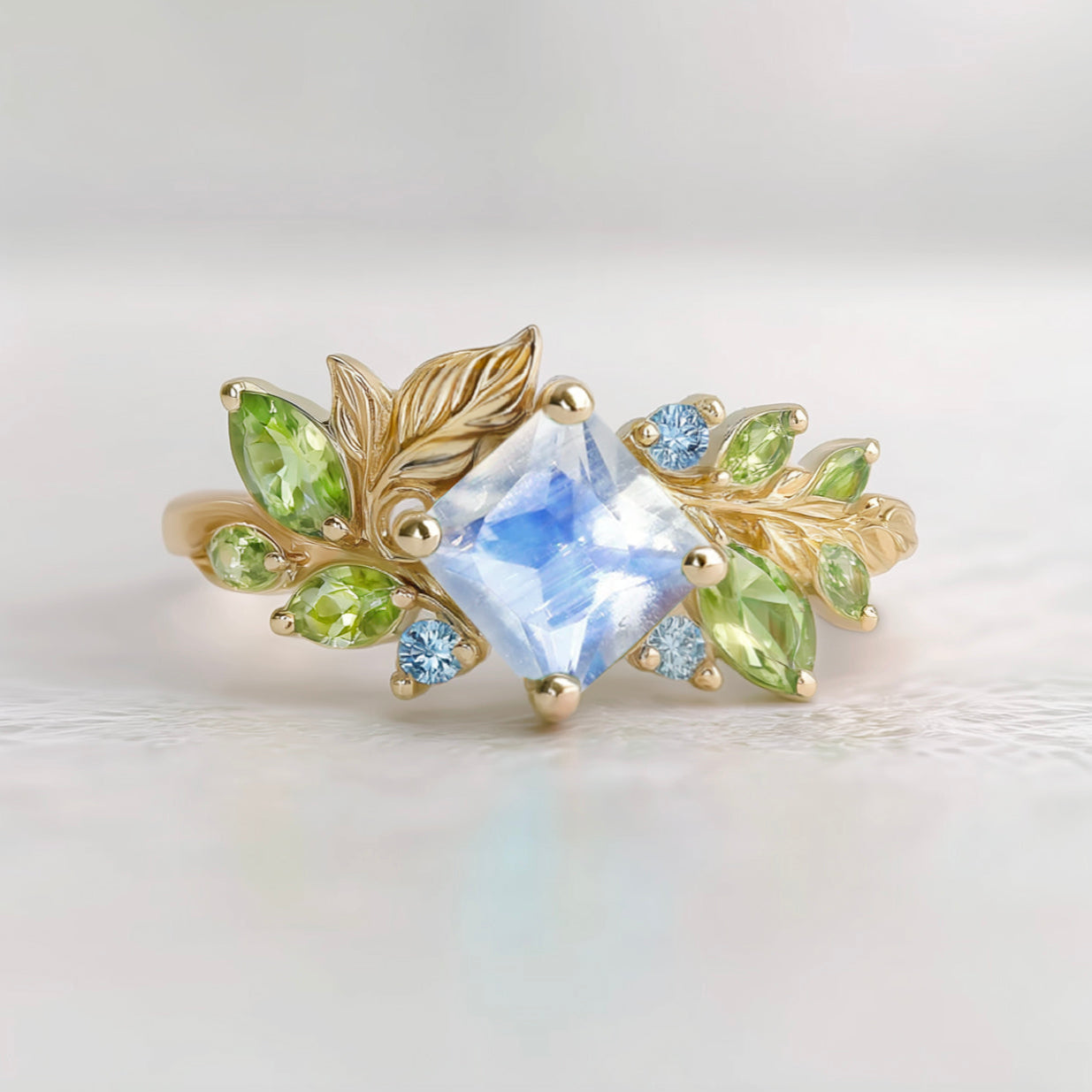 Gold ring with a central blue moonstone and green peridot accent stones 