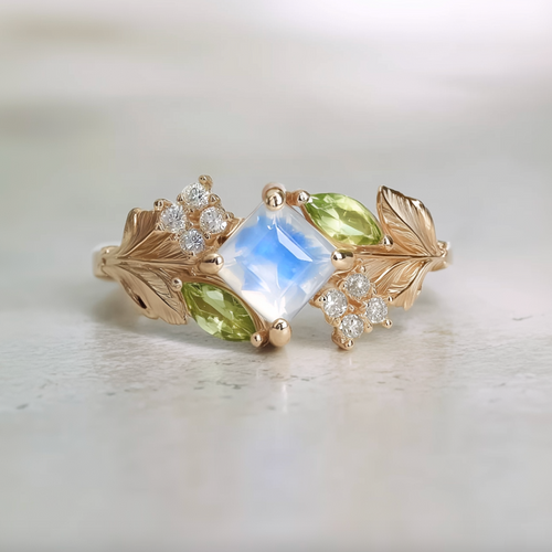 Gold ring with a central moonstone and leaf designs on a light background