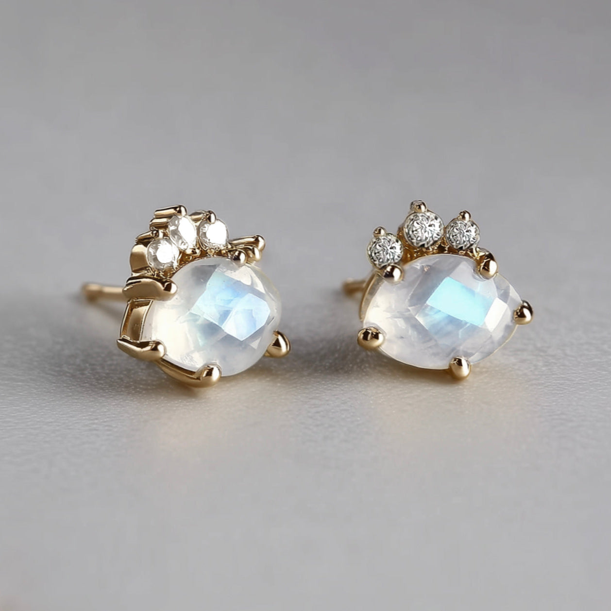 Pair of gold earrings with moonstone stones on a gray background