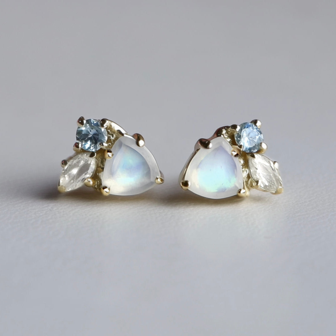 Pair of earrings with moonstone and blue topaz stones on a light gray background