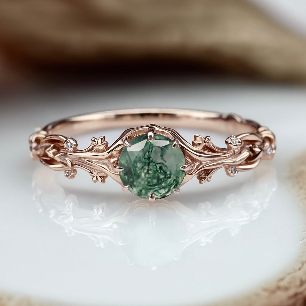 Rose gold ring with a green gemstone on a natural wood background