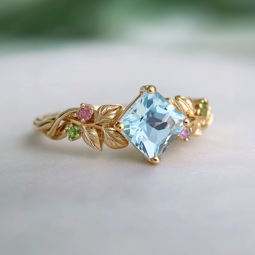 Gold ring with a blue gemstone and small pink and green stones on a light background