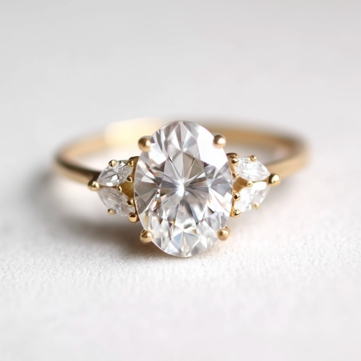 Gold ring with a large oval diamond and smaller stones on a light background