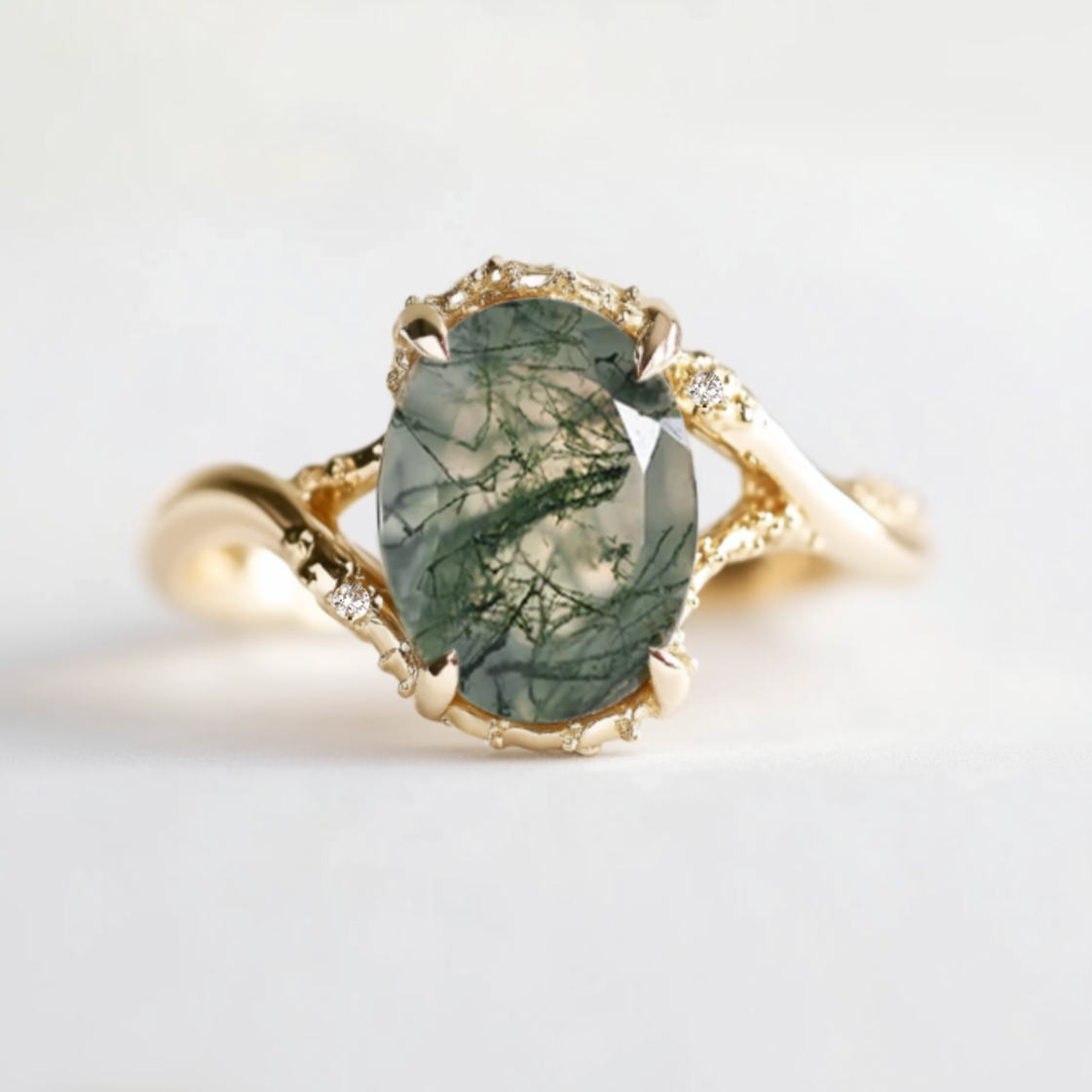 An oval moss agate ring with a textured band and two small accent diamonds, presented on a white background.