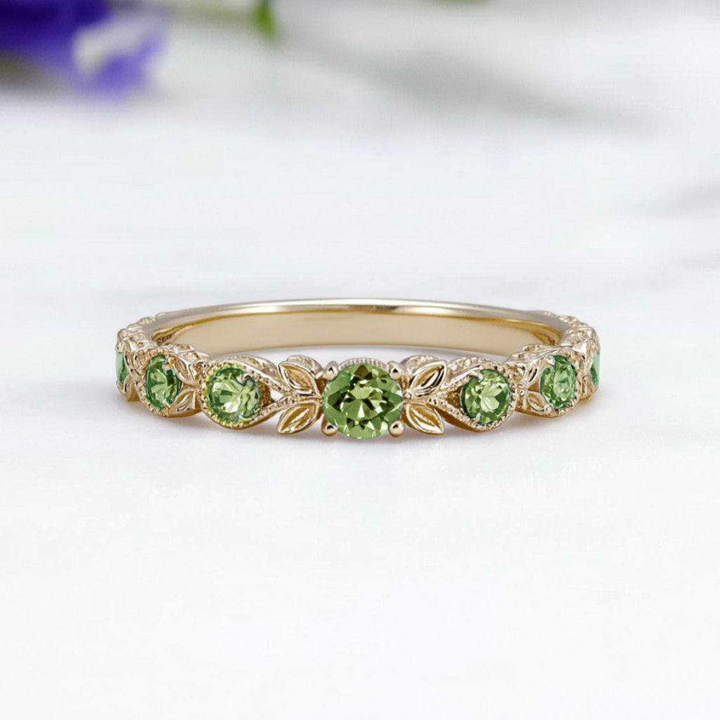 Gold ring with green gemstones on a white background