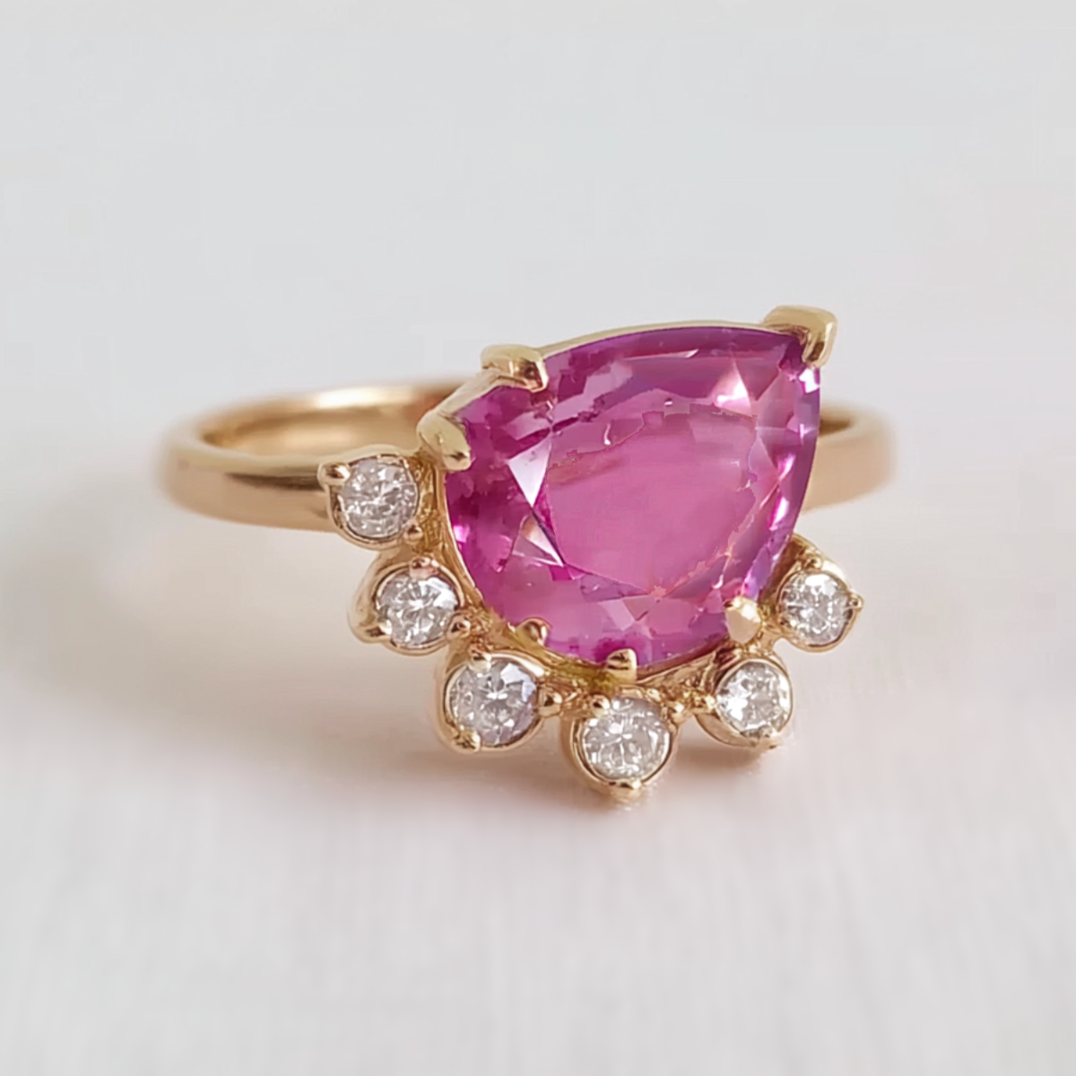 Ring with a pink gemstone and diamond accents on a light background