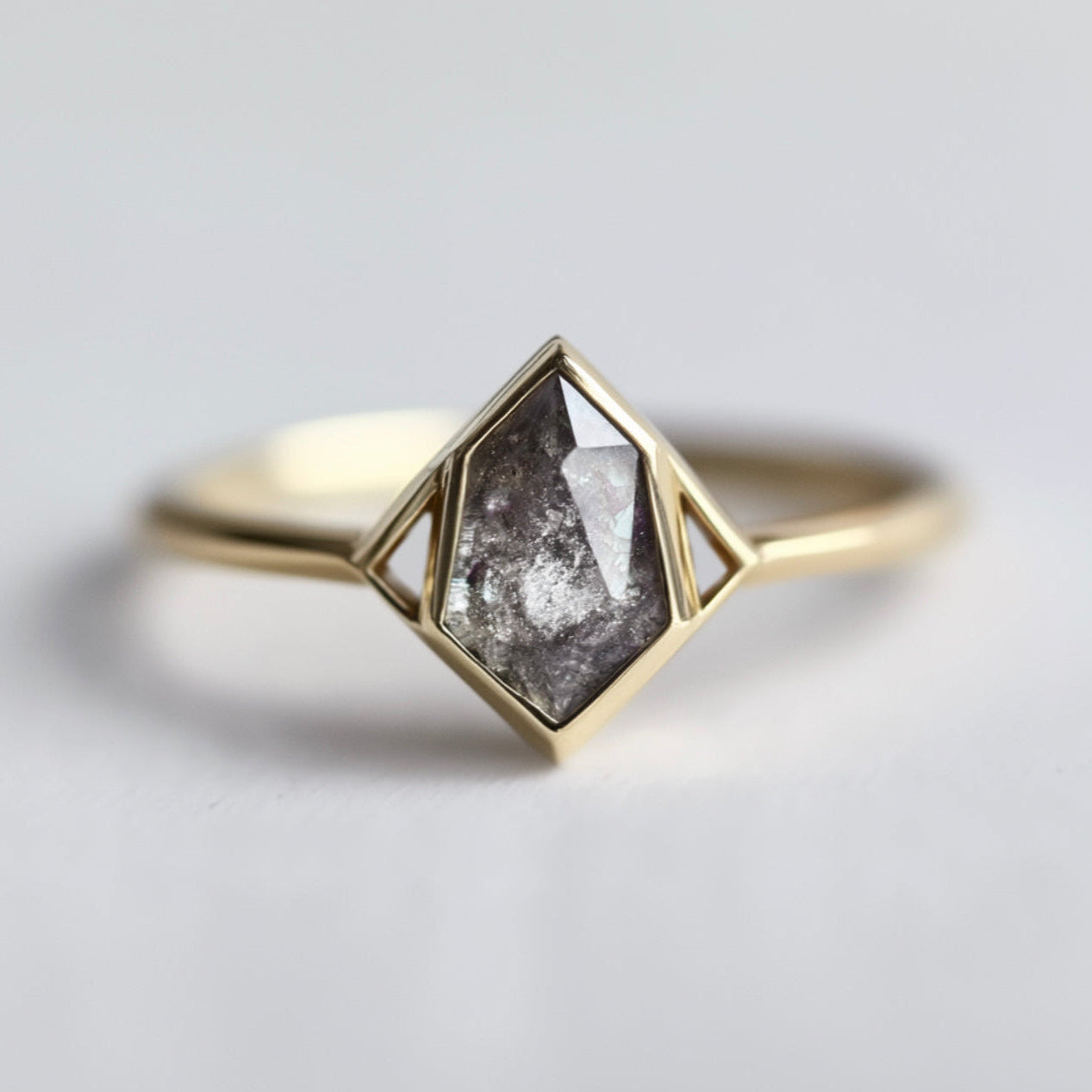 Gold ring with a geometric design and central salt and pepper diamond 