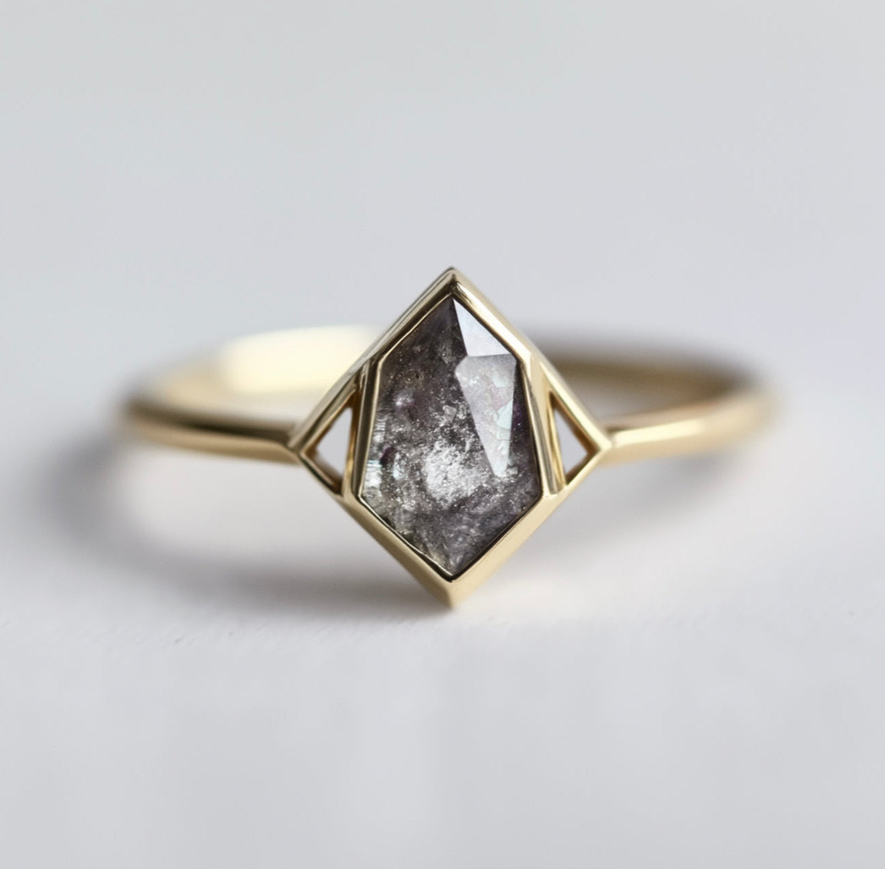 Gold ring with a geometric design and central salt and pepper diamond 