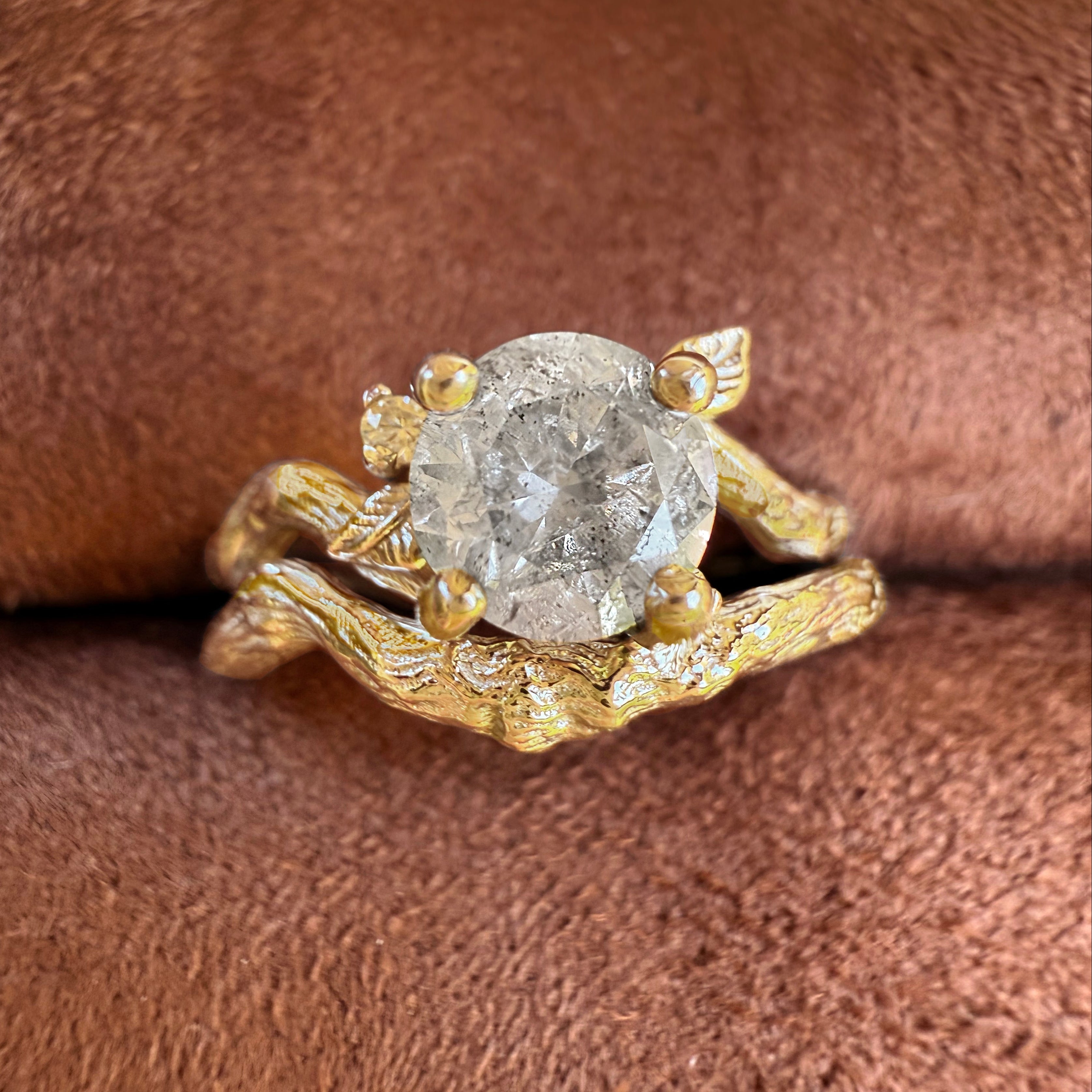 Gold ring with a diamond on a brown fabric background