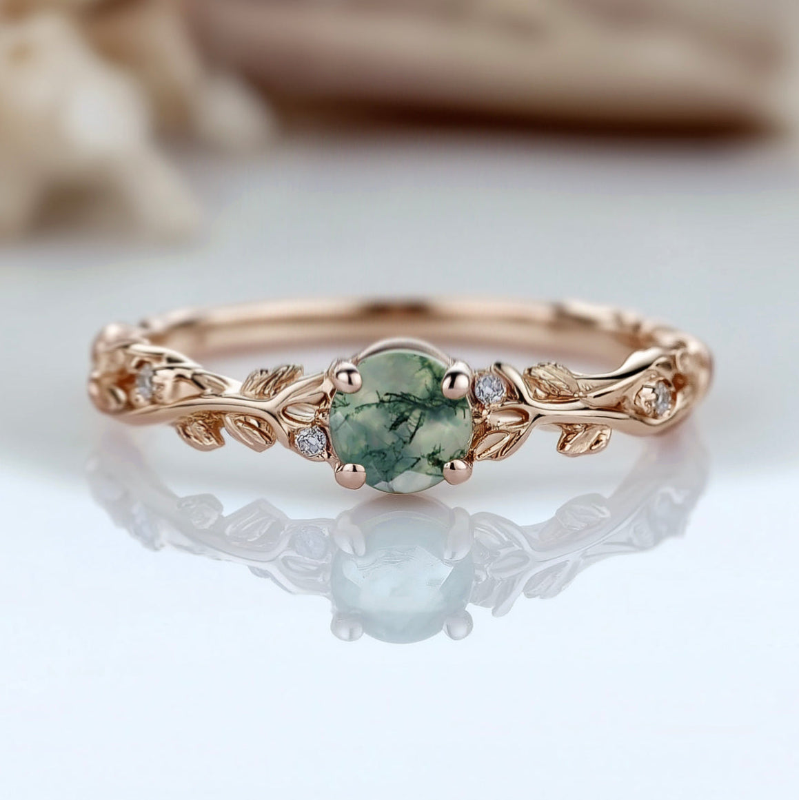 Rose gold ring with a green gemstone on a reflective surface