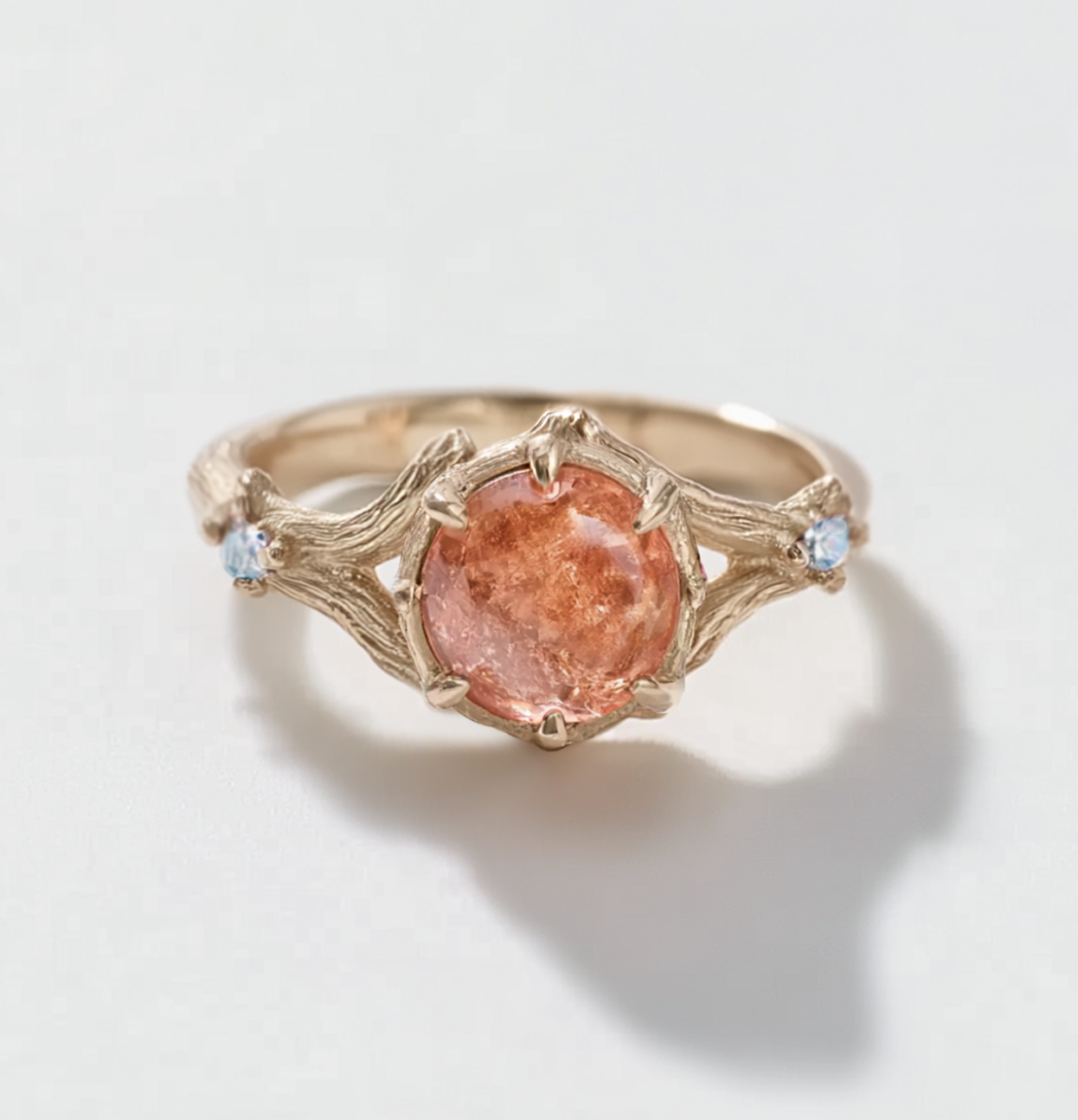 Gold ring with a orange sunstone and blue moonstones on a light background
