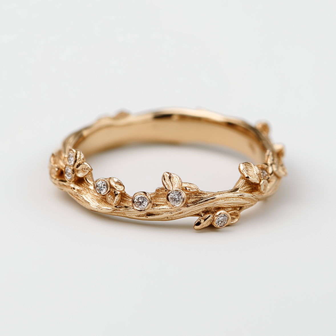 Gold ring with floral design and small diamonds on a light gray background