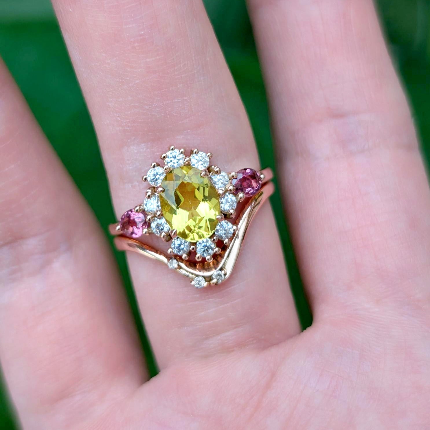 Ring with a yellow gemstone on a person's finger against a green background