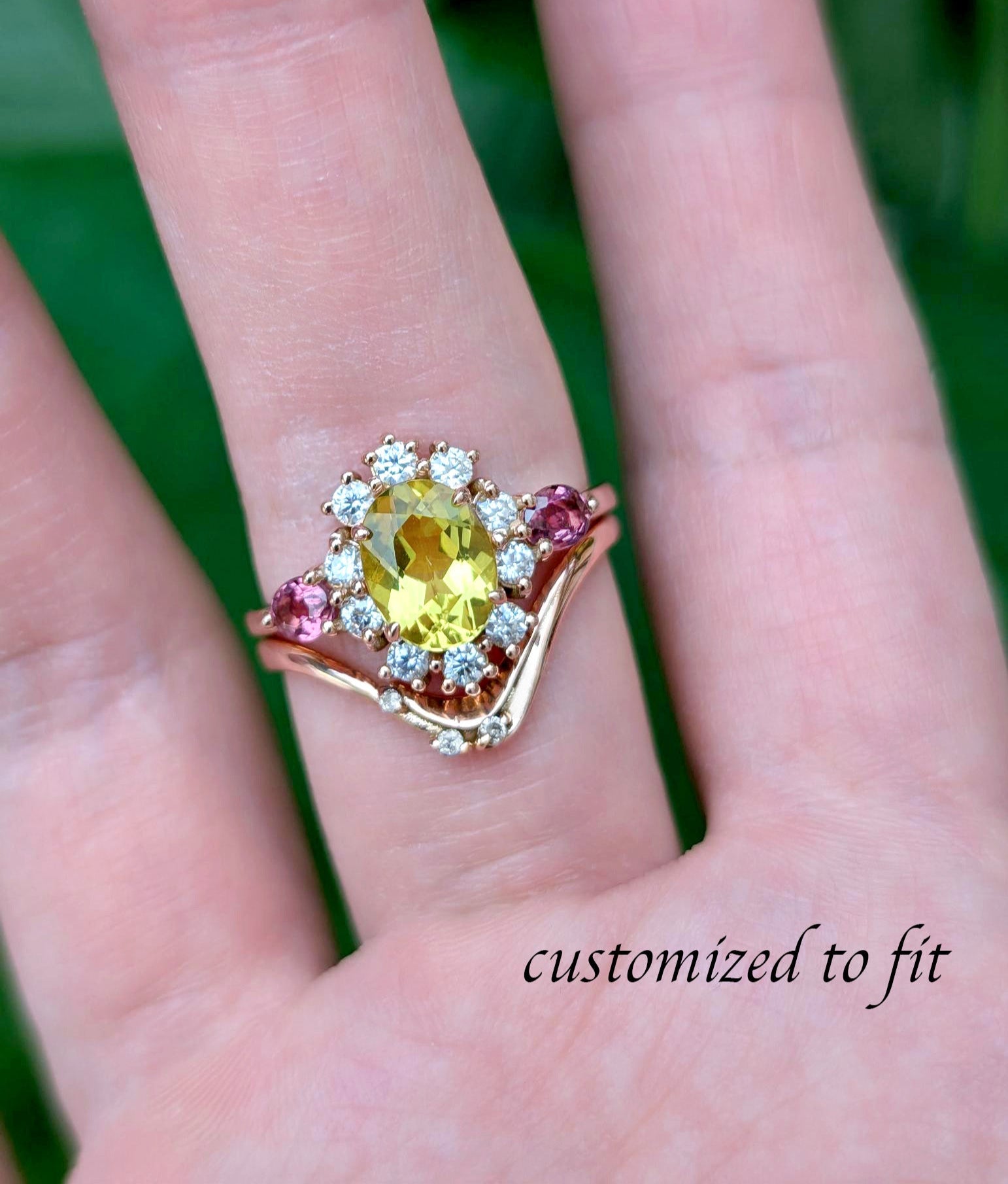 Ring with a yellow gemstone on a hand against a green background