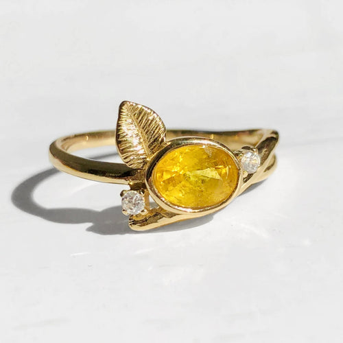 Gold ring with a yellow sapphire and small diamonds on a white background